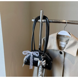 Détail du sac en similicuir noir avec nœud en dentelle blanche et chaîne en cœur