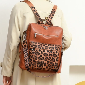 Woman wearing stylish brown faux leather backpack with leopard print straps and pocket