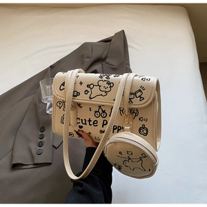 Detalle del bolso de hombro crema con dibujos graffiti de cachorros y estuche pequeño
