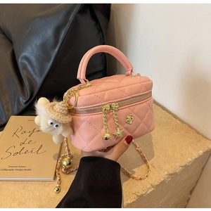 Detailed macro view of pink quilted mini box bag with gold floral clasp and chain strap