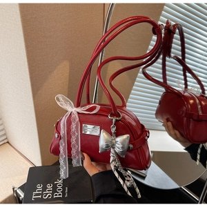 Gros plan d'un sac rouge en cuir verni brillant avec nœud en dentelle et breloques argentées