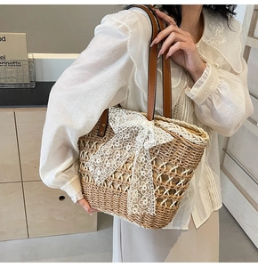 Détail du sac cabas en paille tissé avec grand nœud en dentelle blanche et anses en cuir