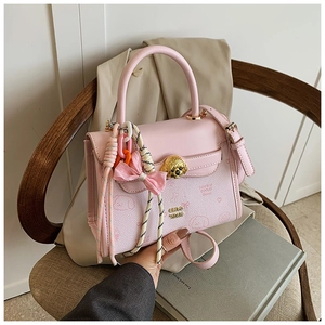 Dettaglio borsa in pelle rosa con fibbia a barboncino dorata e charm intrecciato
