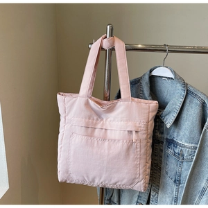 Detailed view of pink quilted tote bag with large front pocket and zipper closure design
