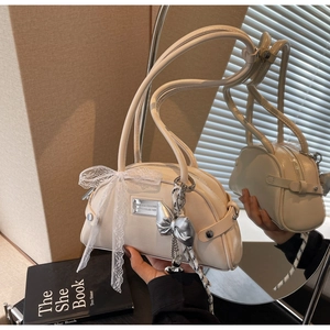 Détail d'un sac à main blanc crème avec nœud en dentelle et breloque papillon