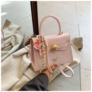 Dettaglio della borsa in pelle rosa con fibbia a cane dorata e charm a sciarpa di seta