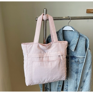 Close-up of pink quilted tote bag showing stitching details and functional front pocket