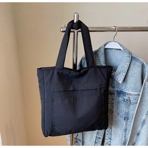 Detail of black tote bag showing multiple front pockets and functional storage compartments