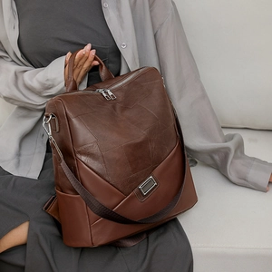 Dettaglio di uno zaino in pelle marrone scuro con design patchwork e fibbia in metallo