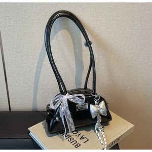 Vue détaillée du sac en cuir verni noir avec nœud en dentelle et breloques argent