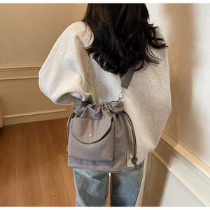 Vista posteriore di una modella con borsa a secchiello in tela grigia e coulisse