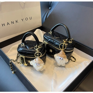 Close-up of black quilted mini bags with gold chain straps and plush charms in a gift box