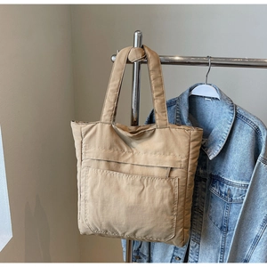 Close-up of a khaki quilted tote bag featuring padded nylon texture and a front pocket