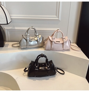 Three glossy leather handbags in silver pink and black displayed on curved stands