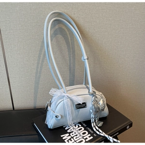 Détail du sac Boston bleu clair avec un nœud en dentelle blanche et un pendentif cœur