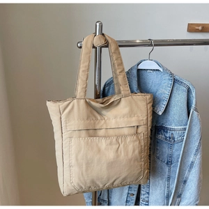 Detail view of the large capacity tote bag featuring a front pocket and wide shoulder straps