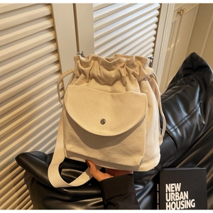 Dettaglio della borsa a secchiello in tela beige con coulisse e tasca frontale