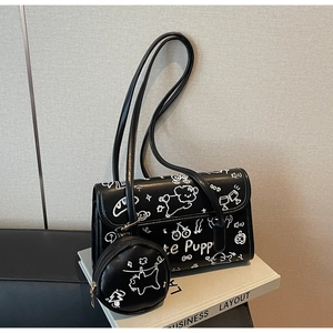 Detalle de bolso de hombro en cuero negro con grafiti de cachorro y monedero redondo