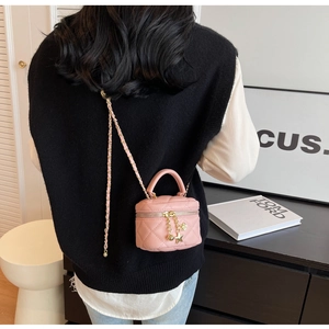 Close-up of pink quilted mini bag with chain strap and star charms worn by a model