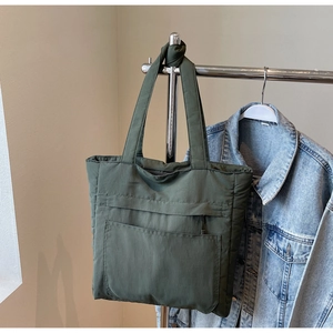Detail of army green nylon tote bag featuring front pocket and durable pleated texture