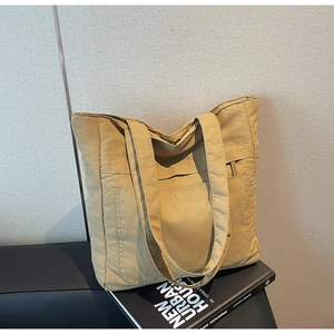 Detail of khaki canvas tote bag featuring two large front pockets and wide shoulder straps