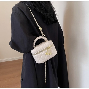 Close-up of quilted crossbody bag with flower charm and golden chain strap