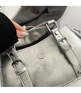 Macro detail of silver pleated handbag featuring a secure metal magnetic clasp closure