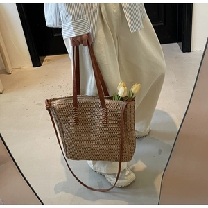 Détails du tissage et des poignées en cuir marron renforcées d'un sac cabas en paille