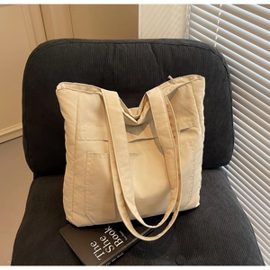 Detail of off-white padded tote bag on black corduroy chair with natural window light