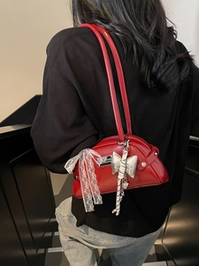 Sac sous le bras rouge en similicuir avec nœud en dentelle porté par un mannequin