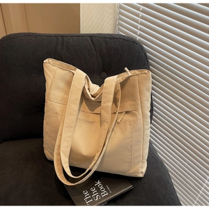 Close-up of beige canvas tote bag with front pocket on a velvet sofa in soft light