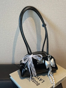 Sac bandoulière en cuir verni noir avec grand nœud en dentelle blanche et pendentif
