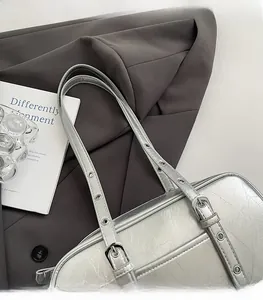 Close-up of silver crinkle leather shoulder bag with adjustable eyelet straps on blazer