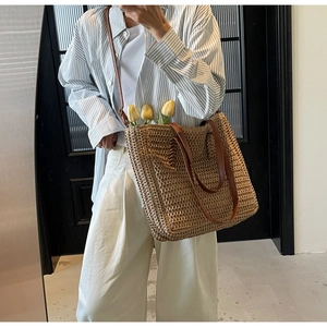 Vue détaillée du sac cabas en paille tressée avec anses en cuir marron et décor floral