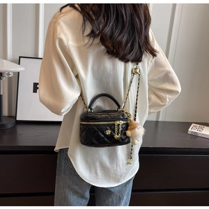 Close-up of quilted black mini crossbody bag with gold chain and plush charm