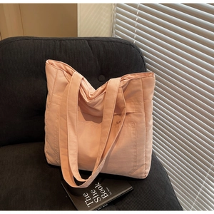 Pink large capacity tote bag with exterior pocket shown on a soft grey sofa