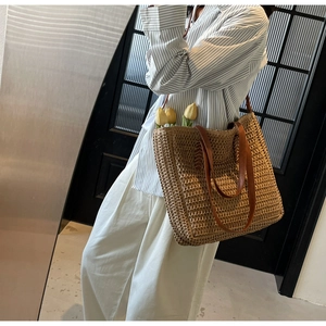 Détail d'un grand sac fourre-tout en paille avec anses en cuir marron et tulipes