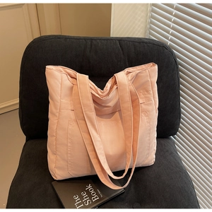 Detail of a pink large capacity tote bag with front pockets on a corduroy chair