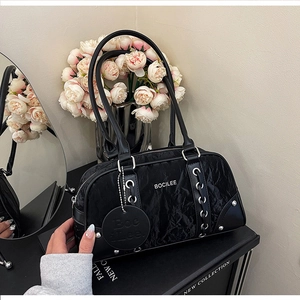 Detail of black Boston bag with ruched texture, side lace-up design and metal pendant