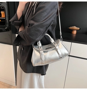 Silver metallic dumpling bag with leather texture and buckled straps shown on a black suit