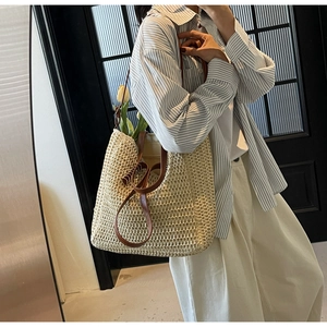 Détail du sac cabas en paille avec bandoulières en cuir marron et tulipe décorative