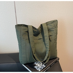 Detail of green quilted tote bag featuring soft padded fabric and front pocket