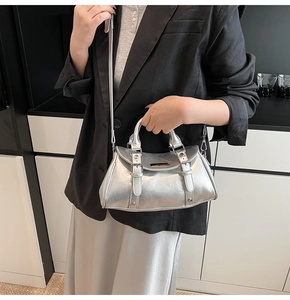 Detail of silver metallic pleated dumpling bag with leather strap buckles and metal plate