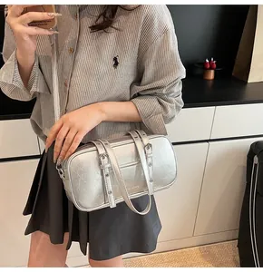 Detail of silver metallic textured Boston bag with buckle straps and adjustable shoulder strap