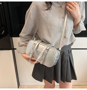 Detail of silver metallic rectangle crossbody bag with buckle straps and textured finish