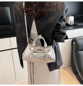 Silver metallic dumpling bag with crinkled texture worn cross-body over a black suit