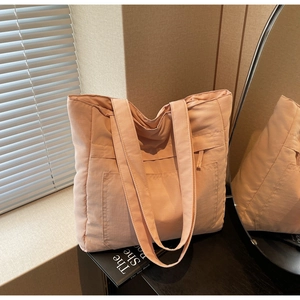 Detail view of pink nylon tote bag with front pocket and wide shoulder straps