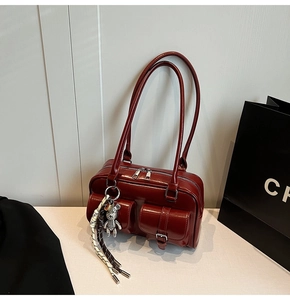 Dettaglio della borsa a spalla vintage rosso scuro in ecopelle con tasche e orsetto