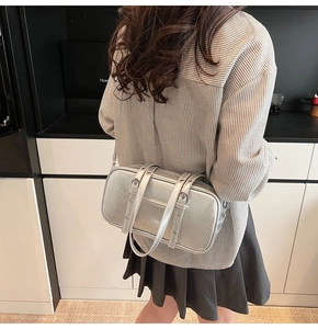 Close-up of a silver Boston bag with a metallic cracked texture and metal buckle details