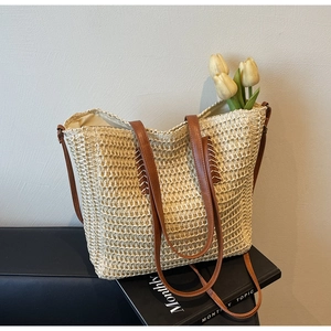 Détail du sac cabas en paille avec anses en cuir marron et une tulipe jaune